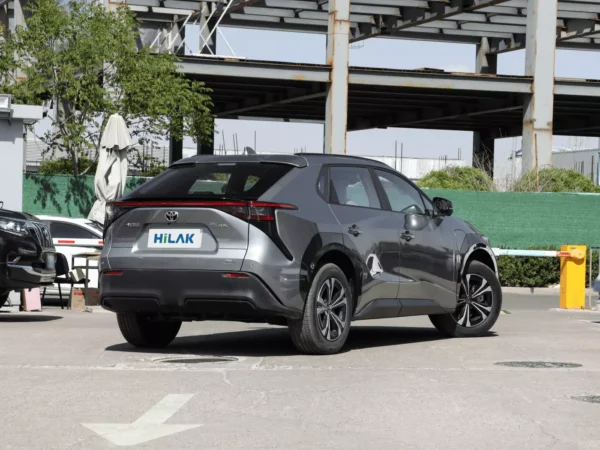 A right rear view of a gray Toyota BZ4X electric car, with the vehicle parked in a concrete parking lot.