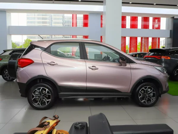 A close-up of the side of a pink and purple BYD Yuan Pro in a vehicle showroom.