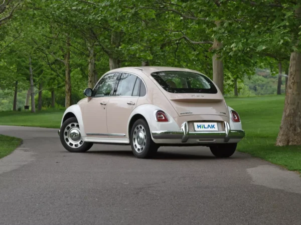 A picture of the left rear view of a cream and white matching Ora Ballet Cat electric car with the vehicle's left front wheel off to the left.