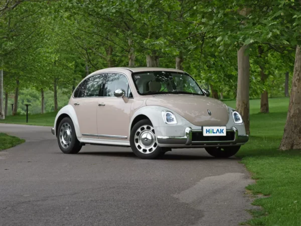 A cream and white Ora Ballet Cat electric car is parked on the curb next to two trees.