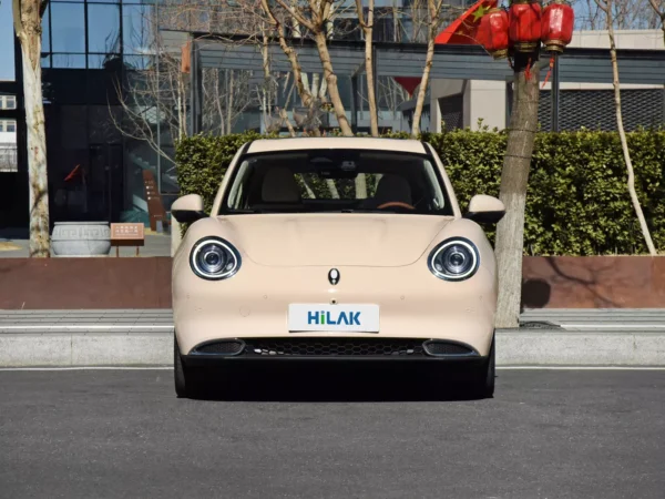 A close-up view of the front of a cream-colored Ora Funky Cat electric car with a Hiluck license plate.