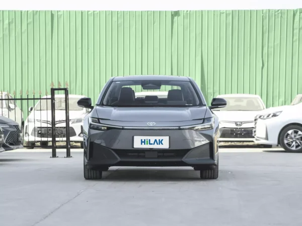 A close-up view of the front end of a gray Toyota BZ3 electric car with glass-covered lights on either side.