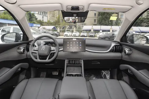 BYD Yuan PLUS premium beige interior with 15.6-inch rotating touchscreen, minimalist dashboard, and ambient lighting in an electric SUV cabin.